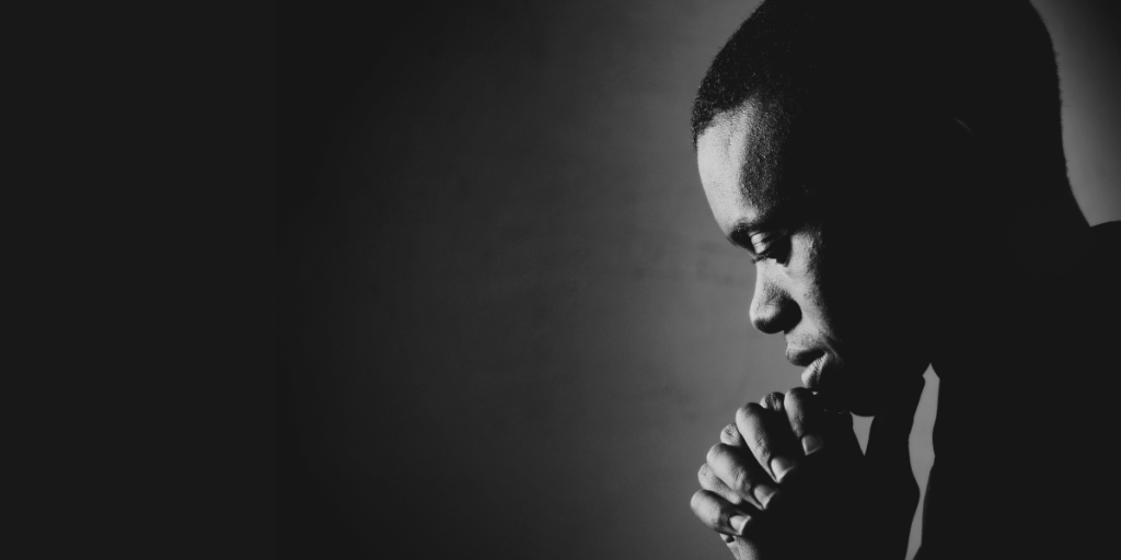 A young man bowing his head in prayer